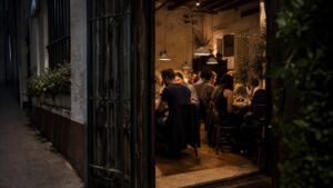 Discreet cozy neighborhood restaurant doorway with diners inside at night