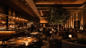 Restaurant dining room with layered pendants, table lamps, wall glow, and softly lit tables